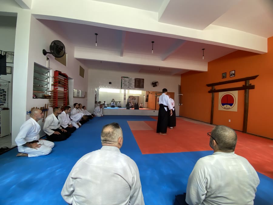 Aluno em reverência tradicional diante do torii e logo do IKE Dojo